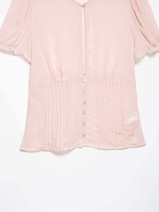 Detail of light pink V-neck chiffon blouse featuring vertical pleated waist and buttons