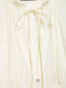 Detail of seersucker shirt with bow tie neckline, pearl button, and elastic waist