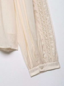 Close-up detail of pleated sleeves and delicate lace inserts on beige chiffon blouse