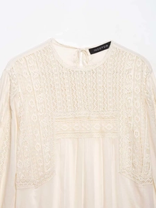 Detailed view of the intricate floral lace embroidery and collar tie on the beige blouse