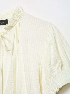 Detail of ruffled high collar and tie strings on cream-colored seersucker blouse