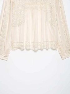 Detail of off-white chiffon blouse featuring intricate floral lace patchwork and textures