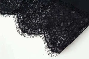 Détail de la bordure en dentelle florale noire sur l'ourlet d'une robe d'été courte