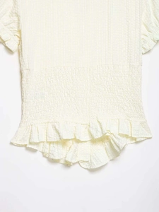 Close-up of yellow seersucker fabric texture with smocked waist and ruffle details