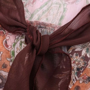 Détail du col d'une chemise imprimé paisley avec un nœud en tissu marron translucide
