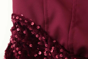 Gros plan sur les paillettes bordeaux et les détails du tissu d'une robe de cocktail