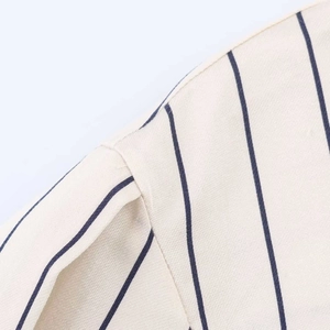 Detailed macro view of the shoulder stitching on a beige striped cotton-linen shirt