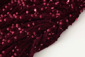 Gros plan détaillé sur un tissu à paillettes bordeaux sur base en velours doux