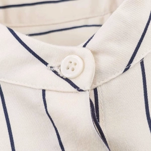 Detailed close-up of the shirt collar with a white resin button and blue striped cotton fabric