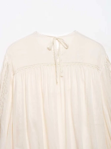 Close-up of cream chiffon blouse featuring delicate lace inserts and pleated details