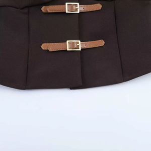 Détail du gilet plissé marron avec doubles brides en cuir et boucles dorées chic