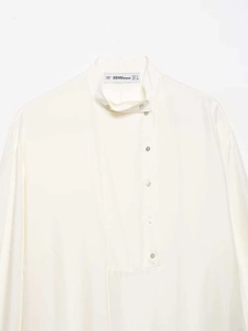 Detailed close-up of cream-white stand collar shirt with elegant offset buttons