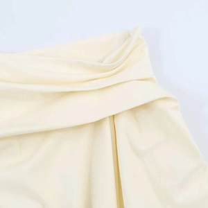 Close-up of cream yellow pleated fabric with unique cross-drape pleated design details