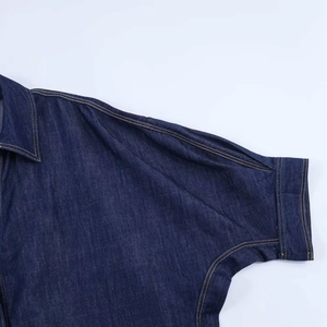 Détail de l'épaule et de la manche d'une chemise en jean bleu foncé avec surpiqûres