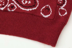 Gros plan sur la maille jacquard à motif cachemire et l'ourlet côtelé du cardigan rouge