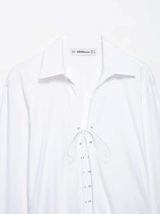 Detailed view of white V-neck shirt featuring metal eyelet lace-up front and soft fabric