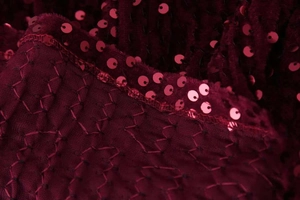 Détail macro de broderies à paillettes bordeaux sur mesh pour une robe de soirée chic