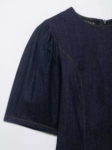 Detail of dark blue denim dress with yellow contrast stitching and puff sleeves