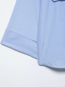 Detailed macro view of light blue striped cotton fabric with precise stitching and hem