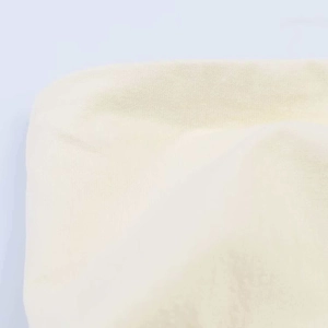 Detailed macro view of beige pleated knit fabric texture and fine stitching for women top