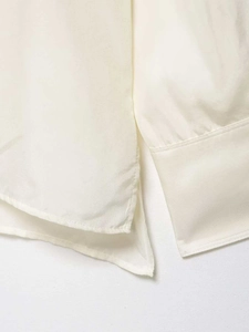 Close-up of precise stitching on the cuff and side slit of this cream long sleeve shirt