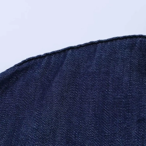 Vue macro de la texture du denim bleu foncé et des détails de couture surjetée