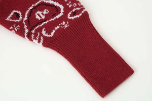 Détail du poignet d'un cardigan rouge avec motif jacquard paisley blanc et bord-côte