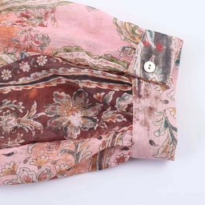 Détail de la manchette à motif cachemire avec bouton perle sur chemisier à fleurs