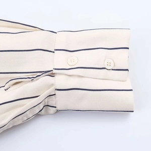 Close-up of striped long sleeve cuffs with white resin buttons and twill fabric texture