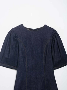 Detailed close-up of dark blue denim dress with puff sleeves and yellow topstitching