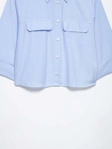 Close-up of light blue striped shirt featuring white buttons and large flap chest pockets