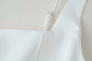 Detailed view of adjustable spaghetti straps and textured white fabric on a summer dress