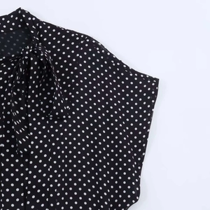 Detailaufnahme eines schwarzen Polka-Dot-Kleides mit Schluppenkragen und weichem Stoff