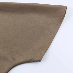Gros plan sur la texture sergée fine et la couture de l'ourlet d'une robe en satin café