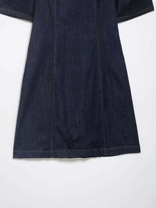 Detailed view of dark blue denim fabric with yellow contrast stitching on a puff sleeve dress
