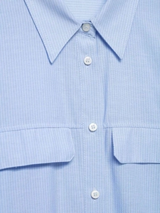 Detailed macro view of light blue striped shirt fabric with chest pockets and white buttons