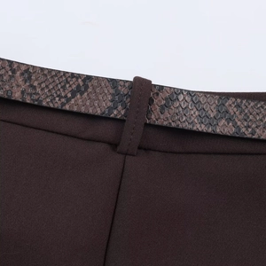 Detail shot of a dark brown trouser waist featuring a snakeskin pattern belt on twill fabric