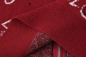Détail du cardigan en maille rouge avec motif paisley blanc et fermeture éclair
