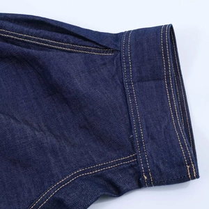 Gros plan de la manche en jean bleu foncé avec détails de double couture orange pro