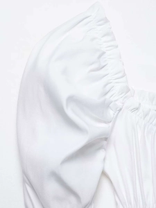 Close-up of white puff sleeve details and pleated waist design on a woven shirt