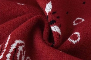 Gros plan détaillé du motif cachemire en jacquard rouge et de la texture du tricot épais