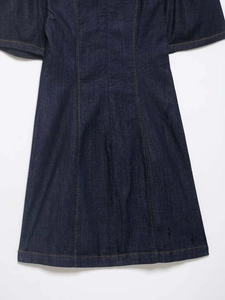 Close-up of dark blue denim dress with orange contrast stitching and fabric texture