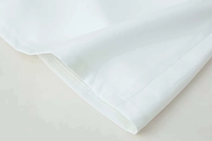 Close-up detail of high-quality stitching and white cotton fabric texture on summer dress