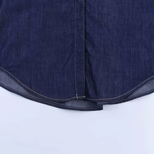 Détail de l'ourlet d'une chemise en jean bleu foncé avec coutures orange contrastées