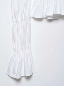 Detailed macro view of white textured fabric with layered pleated flare sleeves and ruffles