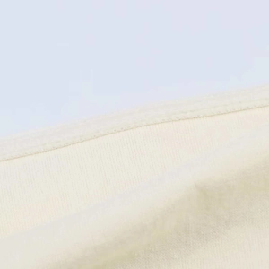 Close-up detail of cream white knitted fabric featuring high-quality double stitching finish