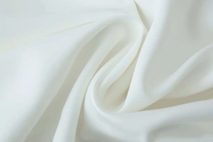Detailed close-up of white dress fabric showing soft texture and fine weave patterns