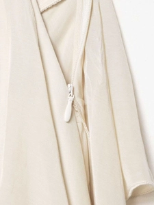 Detail view of the high-quality invisible zipper on a cream ruffle skirt fabric