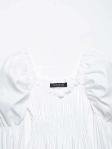 Detail of white square neck blouse featuring ruffled trim and elastic smocked texture