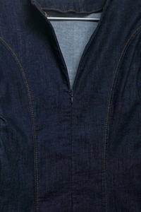 Detail of dark blue denim dress neckline with orange contrast stitching and zipper